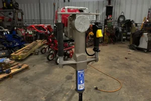 Manual fence post driver tool displayed in a workshop, ideal for installing fence posts