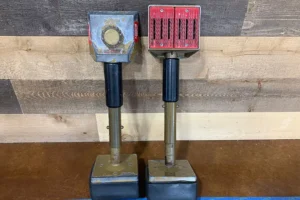 Two knee kicker tools for carpet installation, displayed on a wooden background