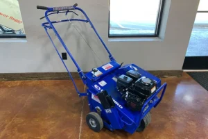 Blue motorized lawn aerator displayed indoors near a window