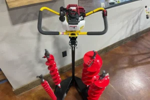 One-man post hole auger with yellow handles and multiple red drill bits on display