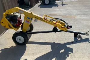 One-man towable auger with a yellow frame on a concrete surface