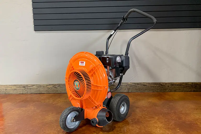 Parking lot blower with an orange fan and black handle on a brown floor