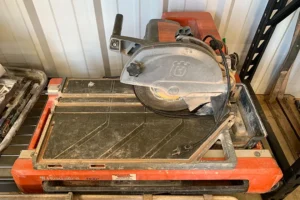 Wet table tile saw with an orange base and black cutting table